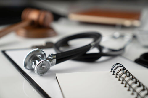 Gavel, notebook and stethoscope on the white table